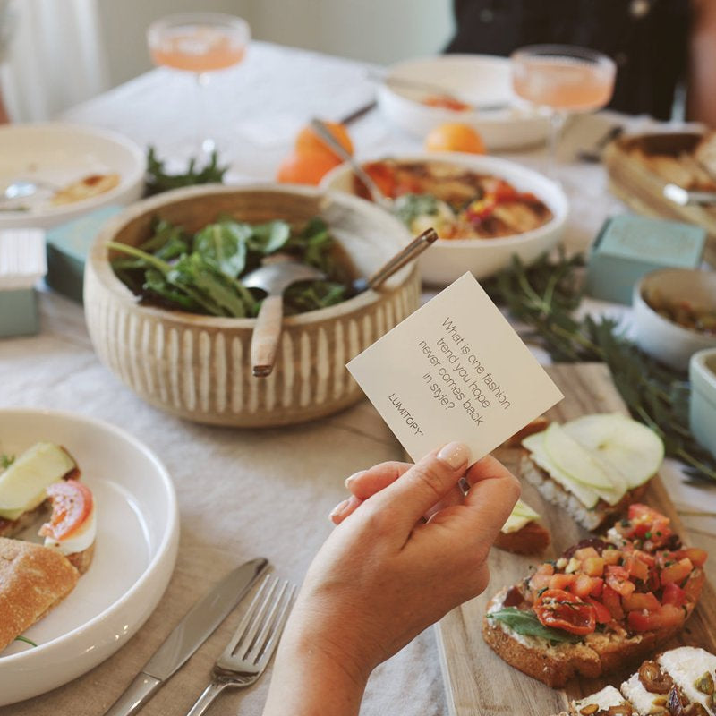 Gathered around the table holding a conversation card about fashion.