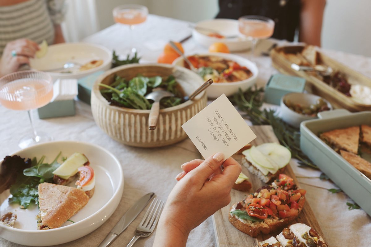 Gathered around the table holding a conversation card about fashion.
